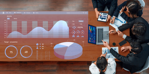 A business team collaborates over a wooden table, engaging in data analysis and discussing performance metrics with digital charts and visualizations. Axiom