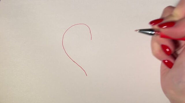 Close-up of a red pen drawing left half of heart outline on white paper. Minimal love concept, handmade sketch, creative process, horizontal video.