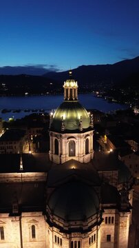 Spectacular vertical drone footage of Como Cathedral at night showcasing the illuminated dome and intricate statues with cinematic effects 5