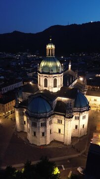 Spectacular vertical drone footage of Como Cathedral at night showcasing the illuminated dome and intricate statues with cinematic effects