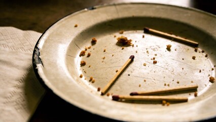 Empty enamel plate showing crumbs and used matches suggesting the end of a simple meal experience