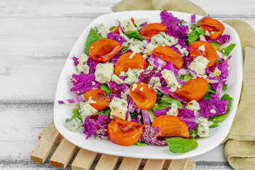 Healthy salad from purple Napa cabbage with persimmon, lettuce, Roquefort cheese and dressing
