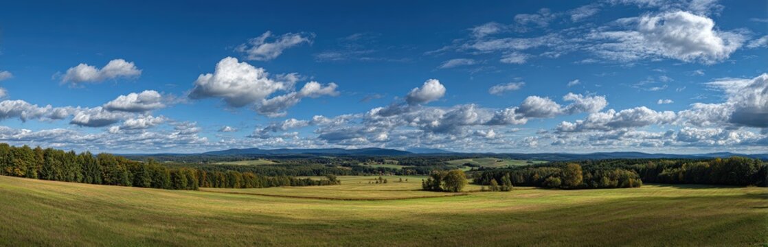 Wide panoramic view of rural landscape with blue sky.