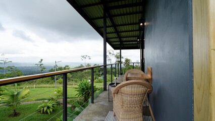 Naklejka premium Eco friendly lodge balcony offering a relaxing view of the lush tropical jungle and valley landscape under cloudy skies in costa rica
