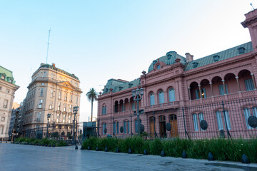 Obraz premium The iconic pink Casa Rosada government building in Buenos Aires, Argentina, stands behind a decorative fence and lush greenery