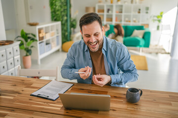 Man laughing during video call meeting in home office