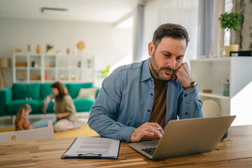 Man concentrating working from home with family in background