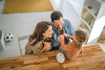 Family teaching daughter about saving money with piggy bank