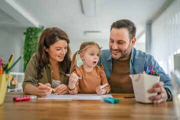 Happy family enjoying creative activity drawing with daughter