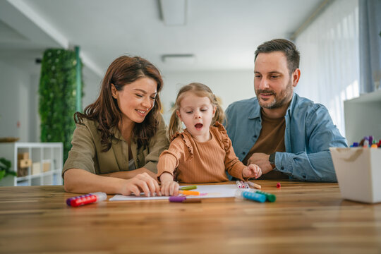 Happy family enjoying creative activity drawing with daughter