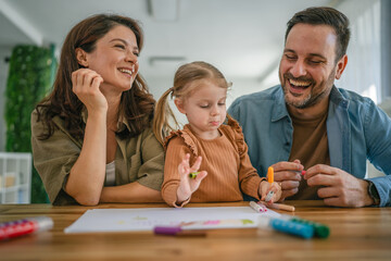 Happy family enjoying creative activity drawing with daughter