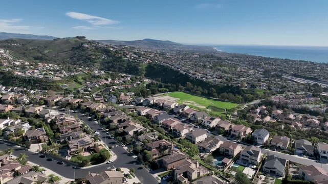 Aerial view over San Juan Capistrano, California, featuring the historic mission, library, sports courts, and an Amtrak train pulling into the downtown station. High quality 4k footage