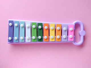 Toy xylophone made of metal and plastic (glockenspiel). A xylophone with colorful keys. The xylophone is placed on a pink background