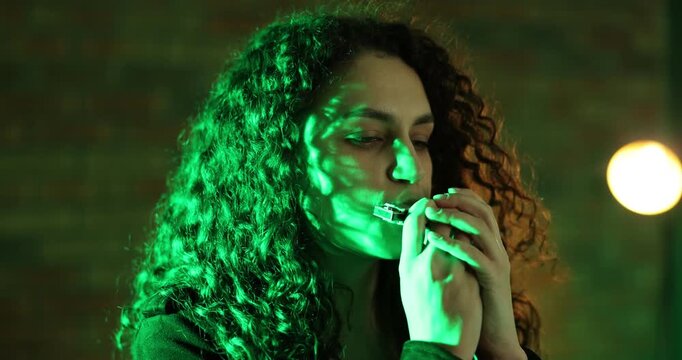 Woman playing harmonica in color lights indoors