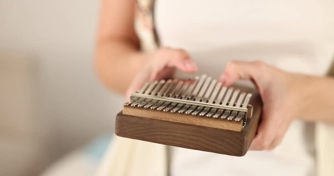 Woman playing kalimba at home, closeup. Musical instrument