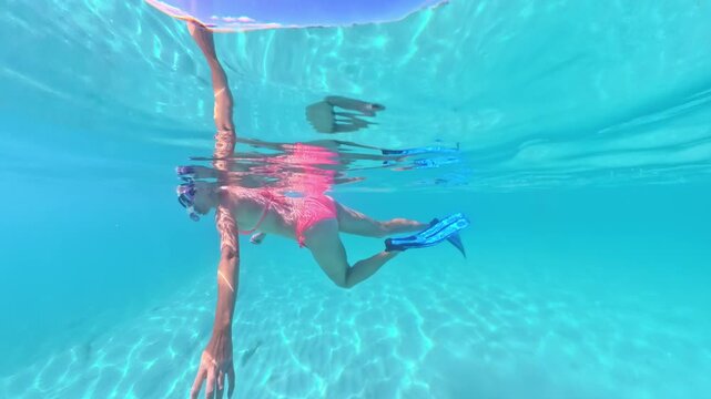 Woman enjoying tropical vacation while snorkeling underwater, wearing pink bikini, mask, and fins in the beautiful, clear turquoise waters of Anse Figuier beach, Martinique, Caribbean of France