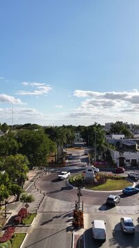 Aerial drone flying forward over Paseo Montejo towards Monumento a los Conquistadores roundabout with palm trees in M&eacute;rida, Yucat&aacute;n. Vertical video