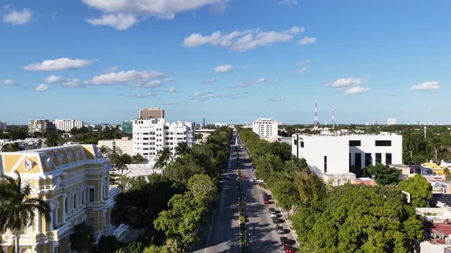 Aerial drone flying forward over Paseo Montejo with colonial mansions, city skyline and clouds in M&eacute;rida, M&eacute;xico
