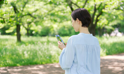 屋外でスマートフォンを使う40代女性　後ろ姿