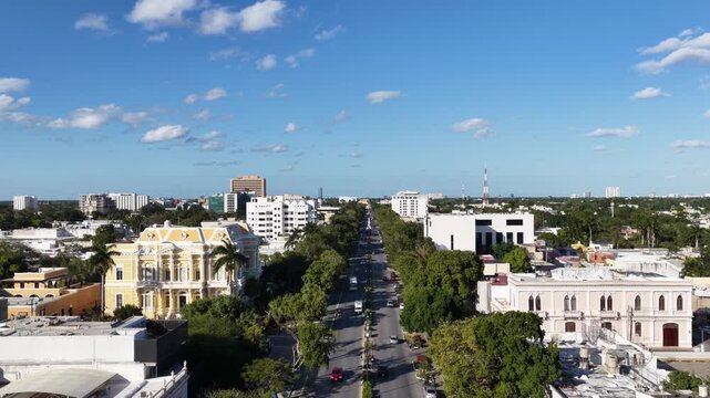 Aerial drone flying forward over Paseo Montejo with historic mansions, traffic and blue sky in M&eacute;rida, Yucat&aacute;n, M&eacute;xico