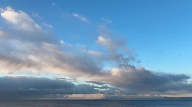 白い雲が流れる青く澄んだ朝の空と穏やかな海の風景