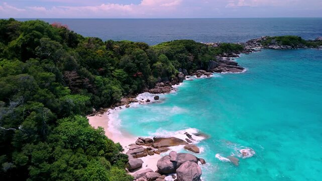 Aerial coastal view of the Similan Islands, Thailand, surrounded by clear blue sea, rocky shore, and white sandy beach.