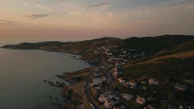 Coastal village nestled in green hills at sunset.