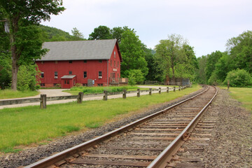 Obraz premium Railroad tracks passing near a red building in Kent, Connecticut