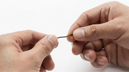 Close up of hands holding and bending a thin dark wire with focus on the tactile action
