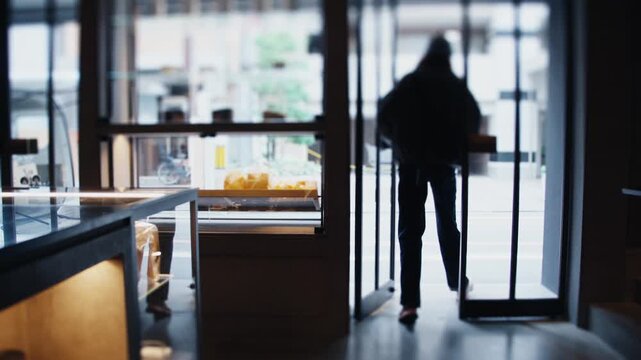 Person leaving modern bakery through glass doors