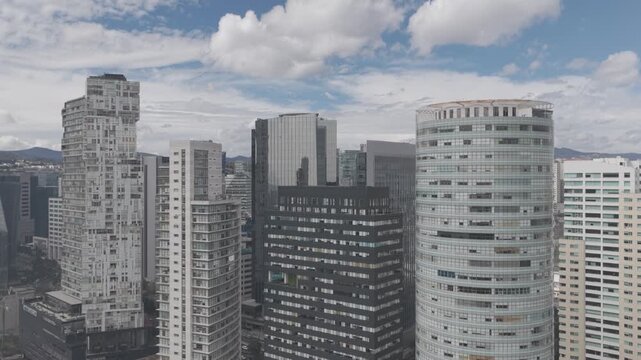 Aerial drone rising in front of Santa Fe skyscrapers revealing urban density with mountains and cloudy sky in M&eacute;xico City. Shot in D-Log M