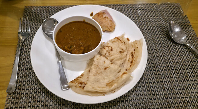 Soft layered parotta served with thick vegetable curry on a neatly arranged breakfast plate.