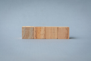 4 square wooden blocks in a row, isolated on light gray background. 