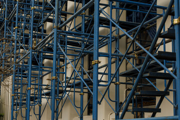 Blue metal scaffolding structure against building wall, showcasing intricate geometric patterns and industrial design. scaffolding is used for construction or maintenance work