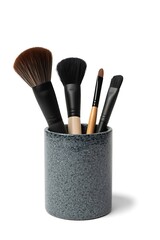 Cosmetic makeup brushes stored in a holder cup on a minimal background for beauty salon and professional makeup concept
