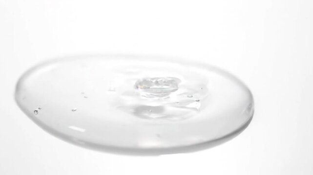 Clear liquid slowly pouring, forming a puddle