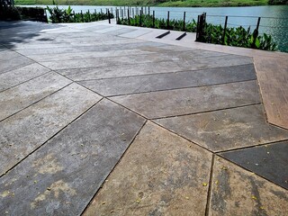 Obraz premium Lake pier extending over calm water beside a lakeside area, wooden dock structure for access and recreation, outdoor waterfront landscape, daylight scene.