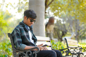 young man wearing sunglasses sitting at garden
