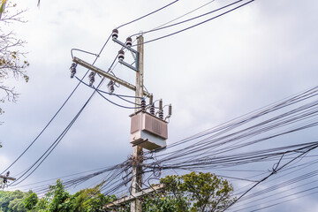 Electrical transformer and dense power lines on utility pole under cloudy sky, urban energy distribution infrastructure