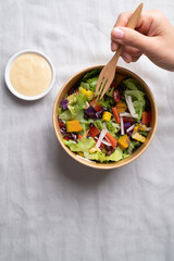 Healthy vegetable salad with lettuce, tomato, pumpkin, corn, purple sweet potato, cabbage, azuki bean and crab stick in takeout bowl eating with salad dressing, Top view