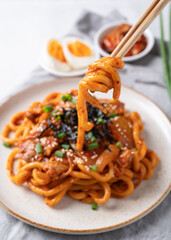 Stir fried Udon noodle with kimchi cabbage, pork, spring onion, sesame seed and seaweed eating by chopsticks