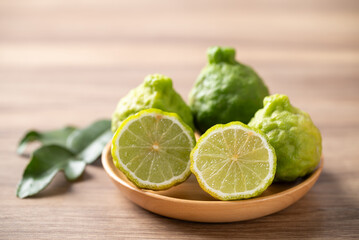 Kaffir lime fruit with leaf on wooden plate, Thai food ingredient