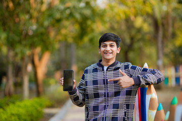 Fototapeta premium young indian teenage boy showing smartphone screen