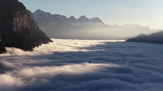 Serene sunrise casting warm glow over snowy peaks framing a sea of clouds near Lake Walensee in the Swiss Alps.