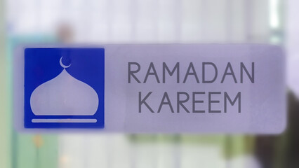 Ramadan Kareem greeting illuminated with a blue mosque dome icon on a modern metallic sign,...