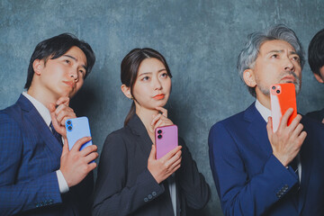 スマートフォンを手に持って悩むビジネスマン