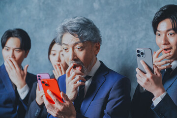 スマートフォンを手に持って驚くビジネスマン