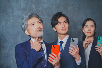 スマートフォンを手に持って悩むビジネスマン