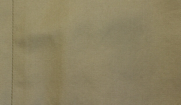 Beige fabric texture. Beige fabric used for trench coat background. Close-up of beige cloth with vertical seam.
