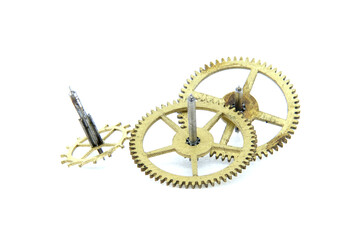 Close-up view of antique brass clock gears and shafts on a white background